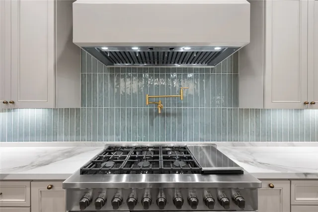 a kitchen with a sink a stove and white cabinets