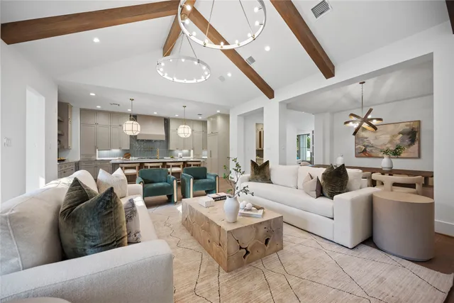 a living room with furniture kitchen view and a chandelier