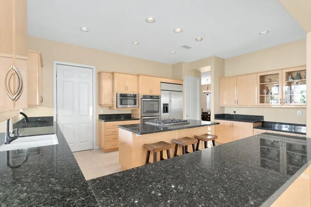 a large white kitchen with kitchen island a stove a sink a refrigerator and windows
