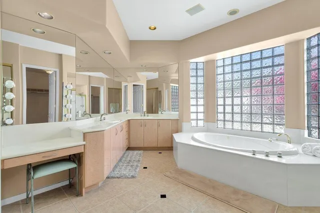 a large white tub sitting in a bathroom next to a window