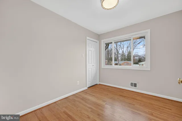 a view of empty room with wooden floor and window