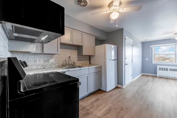 a kitchen with stainless steel appliances granite countertop a refrigerator a sink dishwasher a stove and white cabinets with wooden floor