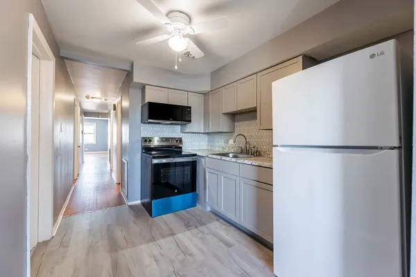 a kitchen with granite countertop a refrigerator stove top oven and sink