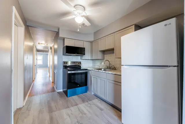 a kitchen with granite countertop a refrigerator stove top oven and sink