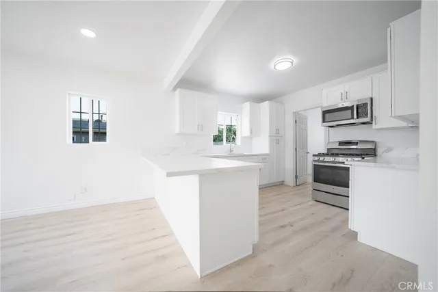 a kitchen with stainless steel appliances white cabinets a sink a stove a refrigerator and white cabinets