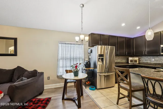 a kitchen with stainless steel appliances kitchen island granite countertop a refrigerator a stove a microwave oven a dining table and chairs with wooden floor