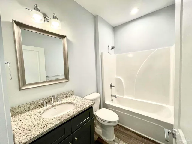 a bathroom with a granite countertop sink toilet mirror vanity and bathtub