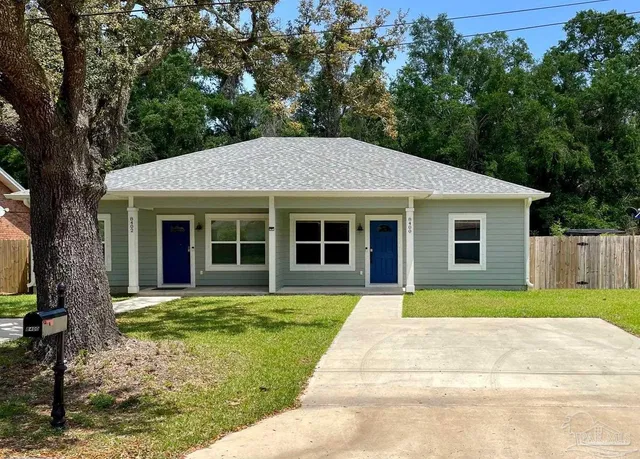 a front view of a house with a garden and trees