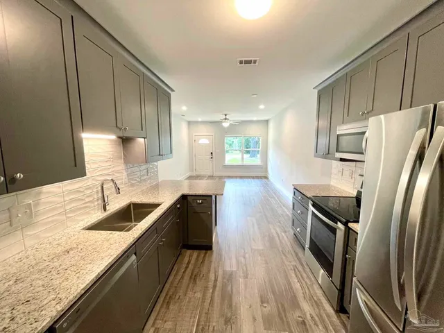 a kitchen with granite countertop a refrigerator a sink a stove and oven