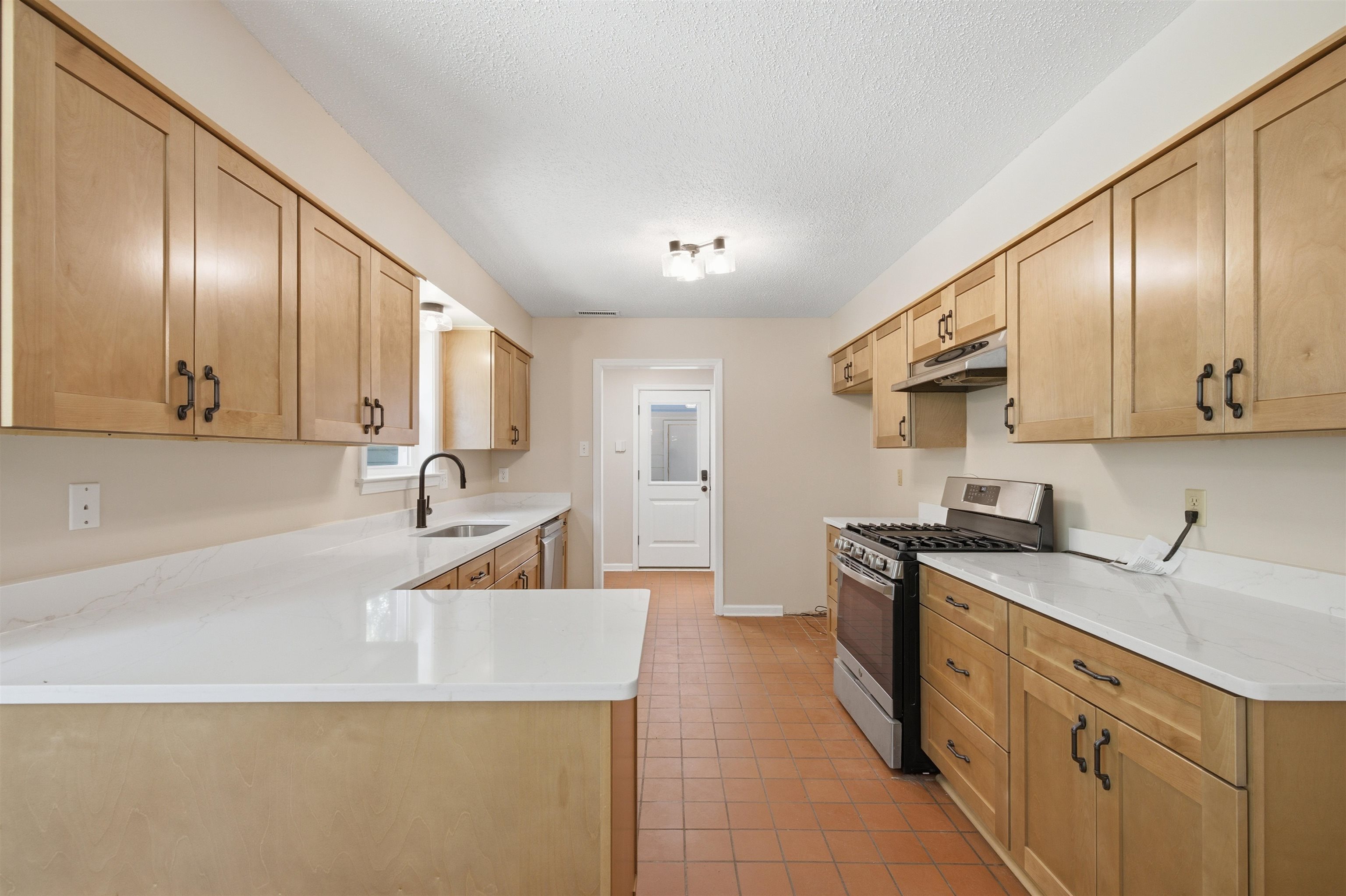 1370 North Reid Hooker Road Eads, TN 38028 - Photo 22 of 39 Kitchen featuring extensive light wood cabinetry, white countertops, stainless steel gas range with overhead vent, and terracotta-toned floor tiling