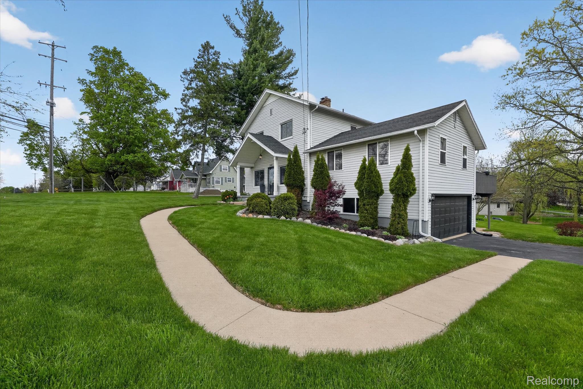 12409 Fenton Road Fenton, MI 48430 - Photo 38 of 61 View of home's exterior featuring a lawn, a garage, asphalt driveway, and a chimney