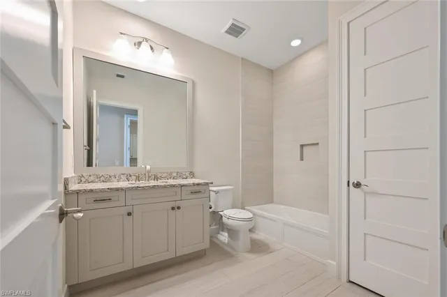 a spacious bathroom with a granite countertop sink a toilet and a mirror