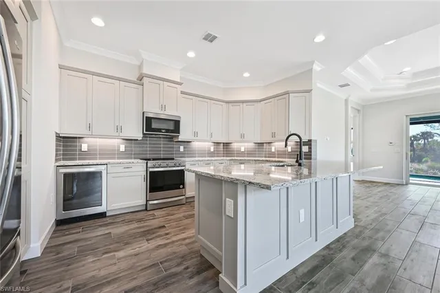 a kitchen with stainless steel appliances granite countertop a stove top oven a sink and a refrigerator