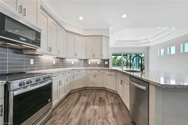a kitchen with granite countertop stainless steel appliances a stove sink and cabinets