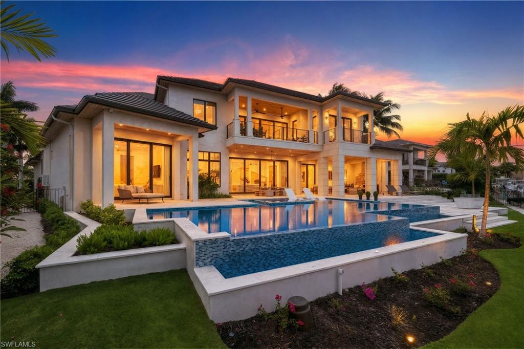 2345 Tarpon Road Naples, FL 34102 - Photo 36 of 43 Back of house at dusk featuring a balcony, an infinity pool, a patio area, ceiling fan, and outdoor furniture