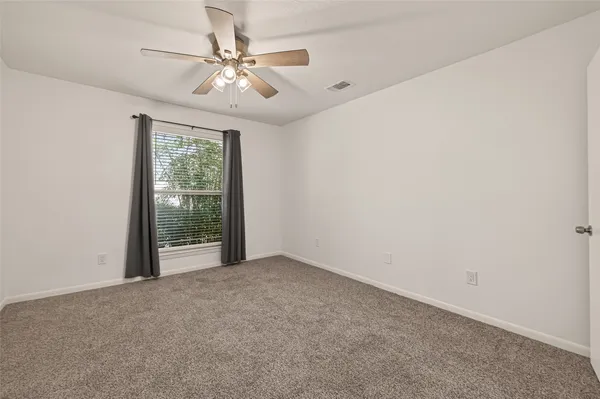 an empty room with windows and ceiling fan