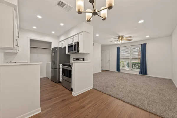 a large kitchen with stainless steel appliances granite countertop a refrigerator a stove top oven a sink and dishwasher with wooden floor