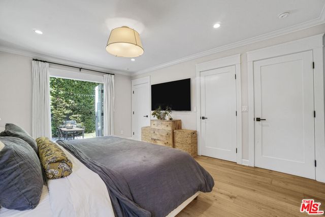 a bedroom with a bed and a flat tv screen on dresser