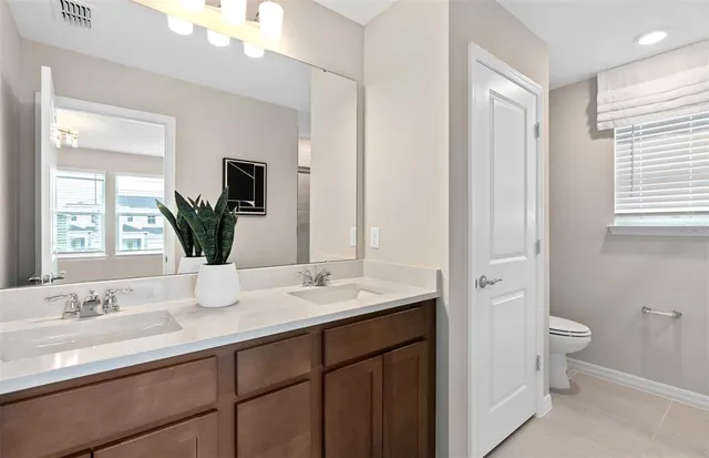 a bathroom with a double vanity sink toilet and a mirror