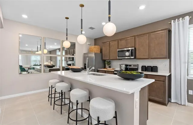 a kitchen with stainless steel appliances a stove a sink island a cabinets and chairs