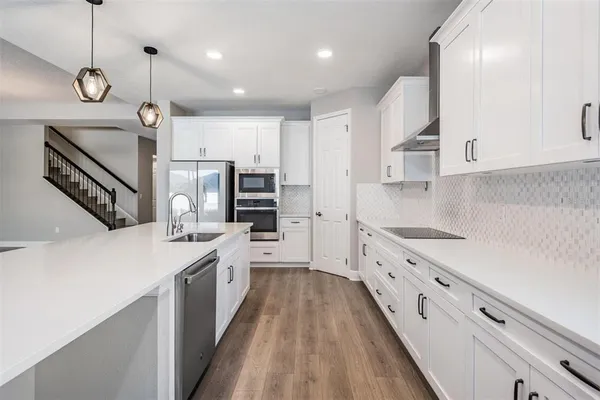 a open kitchen with kitchen island a stove a sink a center island and wooden floor