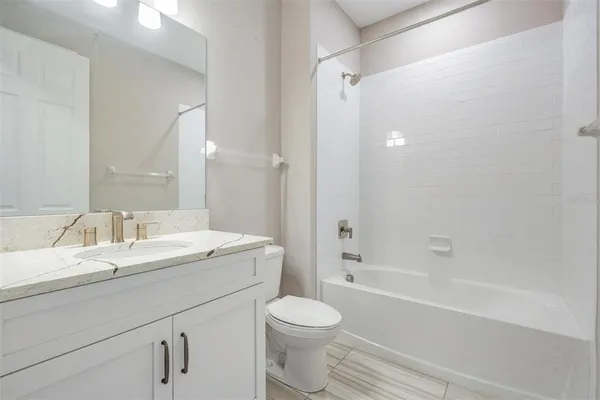 a bathroom with a granite countertop sink toilet a mirror and shower