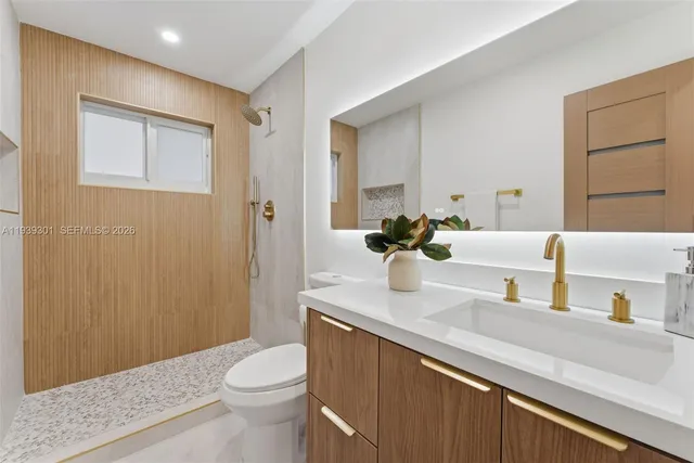 a bathroom with a granite countertop sink toilet and mirror