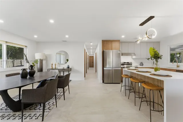 a kitchen with a dining table chairs refrigerator and microwave