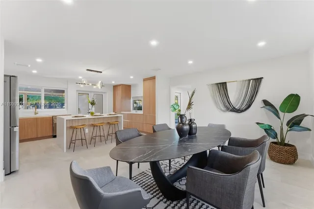 a dining room with furniture a rug potted plant and a large window