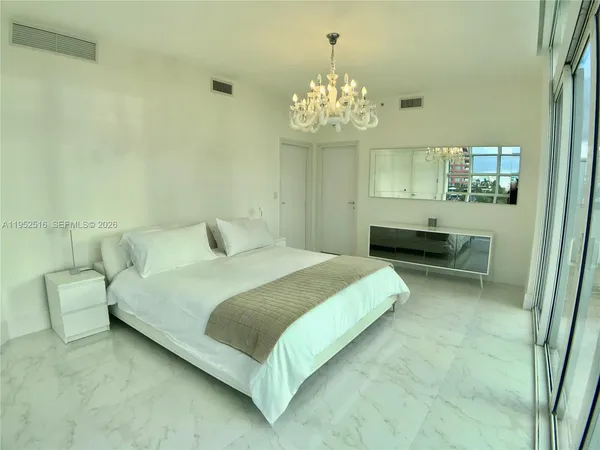 a bedroom with a bed chandelier and a window