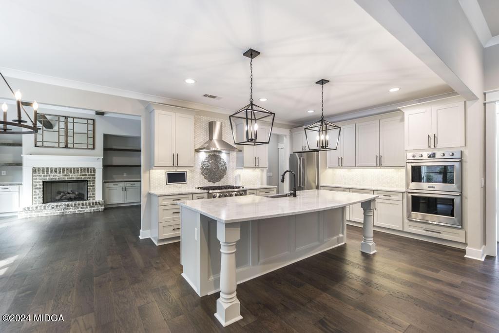 411 Crescent Drive Forsyth, GA 31029 - Photo 17 of 57 a kitchen with kitchen island a stove a sink and a wooden floor