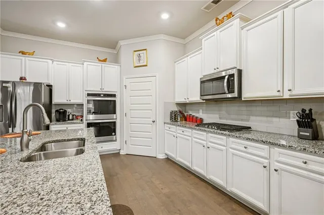 a kitchen with stainless steel appliances granite countertop a stove a sink dishwasher a refrigerator and cabinets with wooden floor