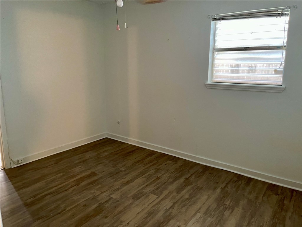 1101 Dewey Avenue Alice, TX 78332 - Photo 14 of 17 an empty room with wooden floor and windows
