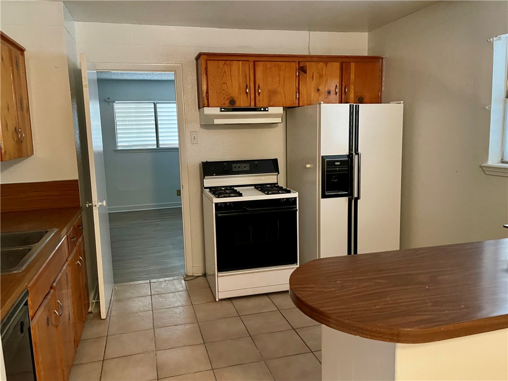 1101 Dewey Avenue Alice, TX 78332 - Photo 5 of 17 a kitchen with granite countertop a refrigerator and a stove top oven