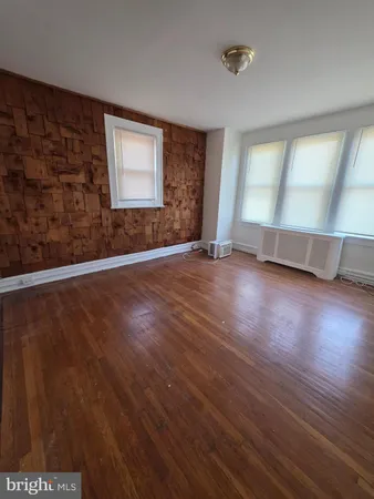 a view of an empty room with wooden floor and closet