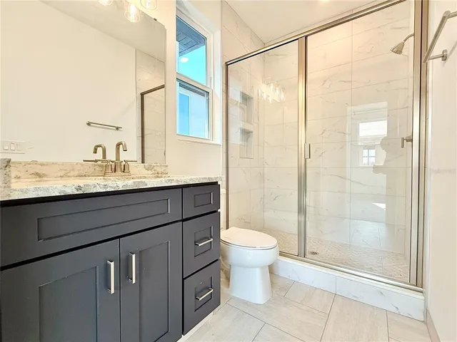 a bathroom with a granite countertop sink toilet a mirror and shower