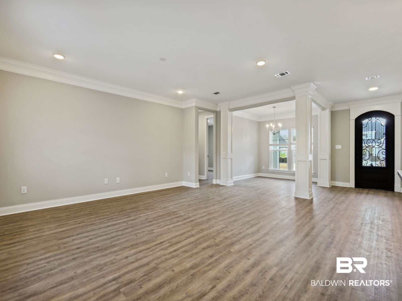 12943 Gondala Street Elberta, AL 36530 - Photo 3 of 23 Unfurnished living room featuring a chandelier, ornate columns, wood finished floors, crown molding, and recessed lighting