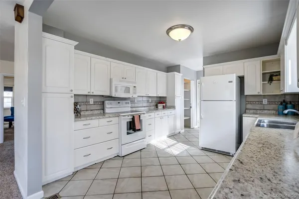 a kitchen with white cabinets and white appliances