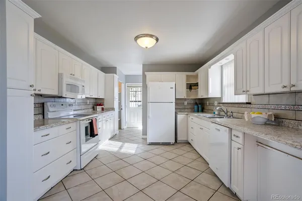 a kitchen with white cabinets and white appliances