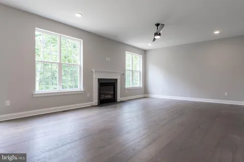an empty room with windows fireplace and wooden floor