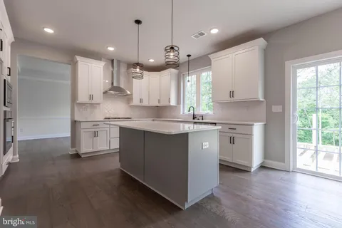 a kitchen with kitchen island granite countertop a sink cabinets and wooden floor