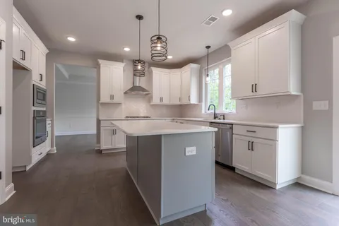 a kitchen with kitchen island granite countertop a sink cabinets and stainless steel appliances