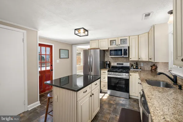 a kitchen with stainless steel appliances granite countertop a sink stove microwave and refrigerator