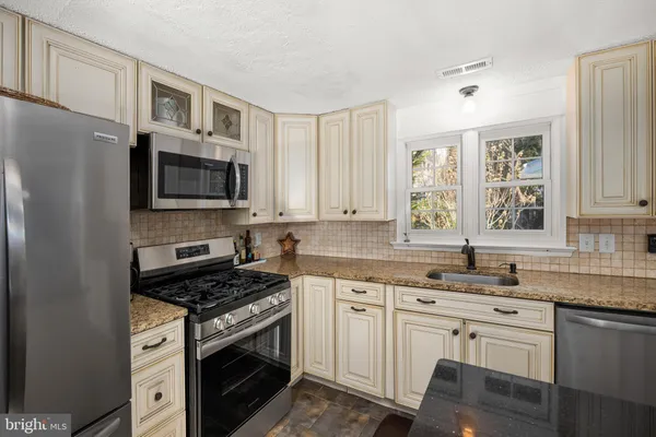 a kitchen with cabinets stainless steel appliances a sink and a window