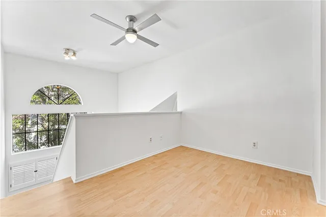 an empty room with a window and a ceiling fan