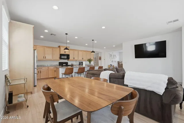 a living room with stainless steel appliances a dining table and chairs