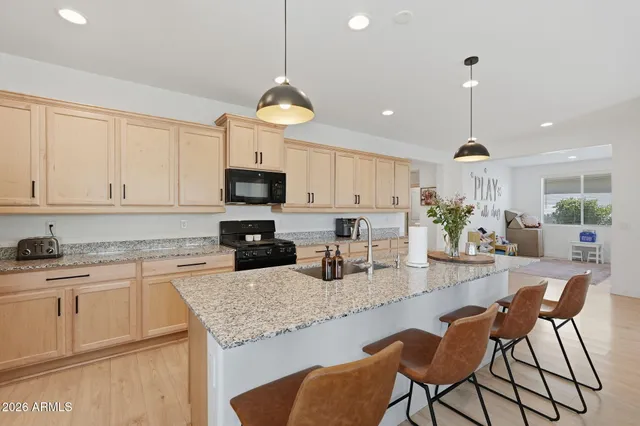 a kitchen with stainless steel appliances granite countertop a stove top oven a refrigerator a sink and white cabinets with wooden floor