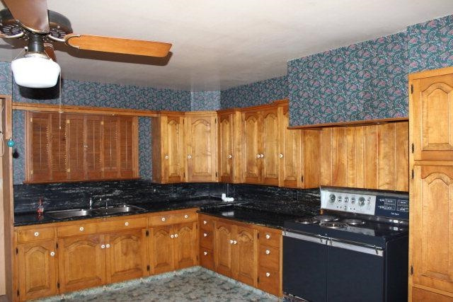 301 Watts Avenue Ralls, TX 79357 - Photo 3 of 10 a kitchen with granite countertop a sink a stove and a wooden cabinets