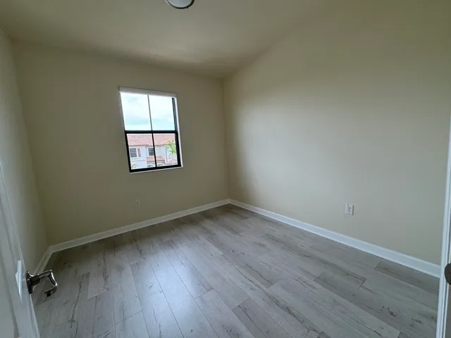 a view of an empty room with wooden floor and cabinet