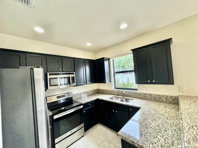 a kitchen with granite countertop a refrigerator stove and sink